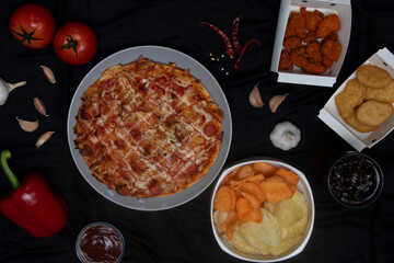 Pizza Party with Side Dishes on Black Background