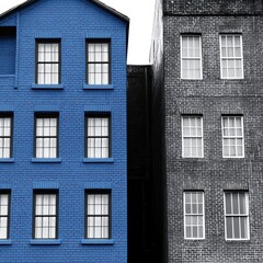 Obraz premium Bright Blue House Among Gray Buildings in Urban Setting