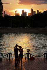 Silhouette of couple learning to dance by the river in a city