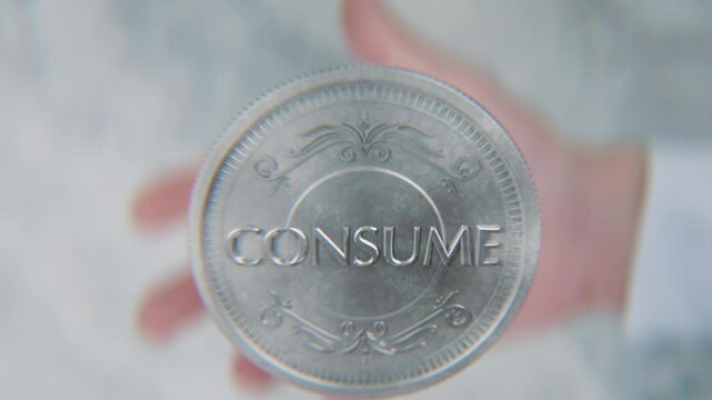 A hand flips a coin marked Create and Consume, spinning toward the camera in slow motion