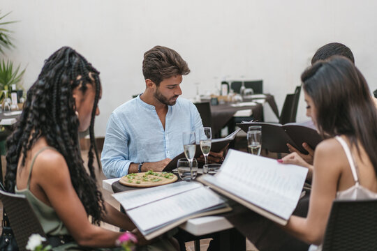 Group of friends reading menus and enjoying drinks during an elegant dinner
