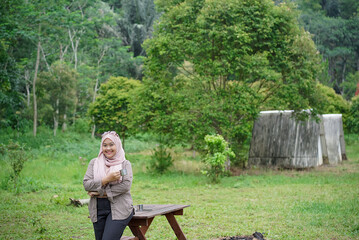 Young Indonesian woman wearing hijab enjoying the calming natural atmosphere while enjoying a cup...