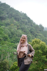 Naklejka premium Young Indonesian female traveler wearing hijab looking for direction while traveling in nature, travel concept.