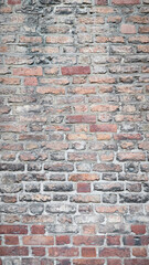 Fototapeta premium Weathered Vertical Brick Wall - Rustic Red and Gray Bricks with Aged Texture, Ideal for Architectural Backgrounds