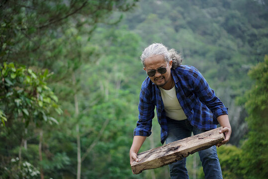 Indonesian male traveler with curly hair making a campfire while traveling in the forest, travel concept.