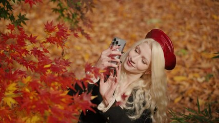 Lithuanian woman smiling while photographing colorful Japanese Maple leaves in Yangjae Forest Park, festive autumn scene, front view downward angle as she looks up