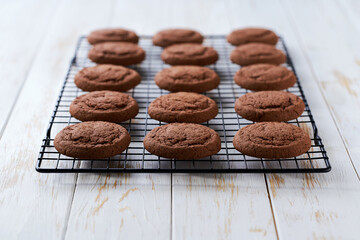 Chocolate brownie cookies in a black wire rack on a white table, close up.