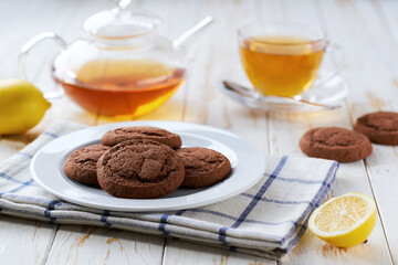 Tasty Chocolate brownie cookies and black tea on a light kitchen table, selective focus.