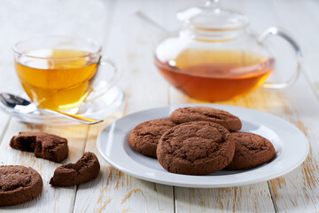 Chocolate brownie cookies and tea on a white table, close up.