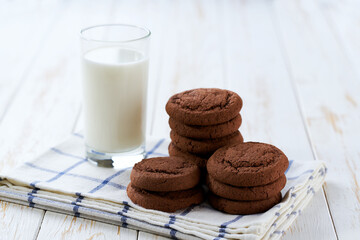Chocolate brownie cookies and milk on a white table, close up.