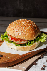 hamburger with green salad, tartar sauce, ketchup, sesame bun, on a dark background with sauces, fast food, snack