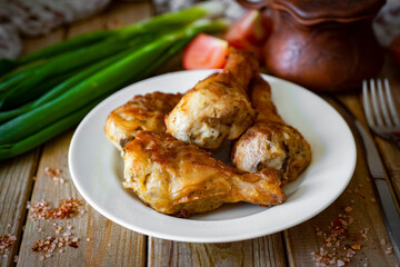 Grilled chicken legs on a white plate on a wooden table. Fried chicken legs for lunch. Close-up.