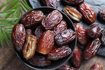 Tasty dried dates and leaves on wooden table, flat lay