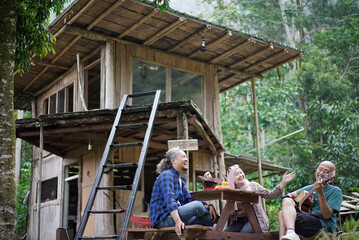 Indonesian man and woman in hijab relaxing in front of forest cabin, travel concept.