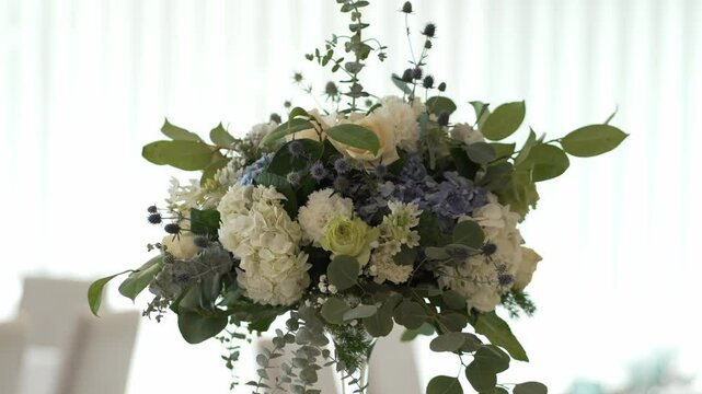 Elegant floral arrangement with white and blue flowers, greenery, and soft lighting