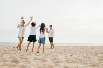 A smiling father and mother with their children son and daughter on a beach adventure. Running playing and laughing creating carefree moments of family joy and happiness under the sun.