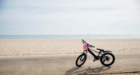 Obraz premium Enjoy the freedom of cycling by the sea, A child's bicycle on a sandy beach under a clear sky creating serene and beautiful seascape perfect for summer tourism adventure. bike in summertime vacations