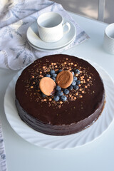 chocolate sacher cake decorated for party. neutral white background with kitchen elements. homemade chocolate cake.