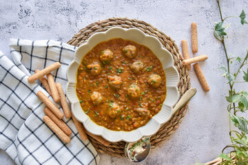lentil dish with meatballs. homemade recipe and neutral background with bread and kitchen towel.