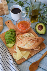 mediterranean breakfast of toast with tomato and avocado, cheese and coffee.