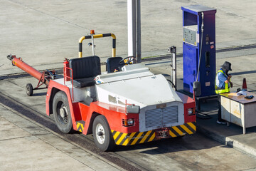 A tractor for pulling luggage carts pumps fuel at a gas station at the airport
