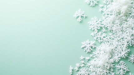 Obraz premium Thin, translucent snowflakes with a shimmering glow scattered gently on a soft mint green background, with ample blank space on the right for adding text, logos, or creative designs.