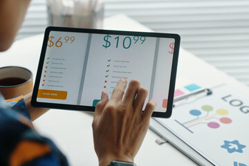 Hand of unrecognizable woman working on subscription service design, using digital tablet in modern office