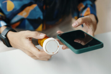 High angle closeup of hands of unrecognizable woman searching information about pills in Internet on smartphone