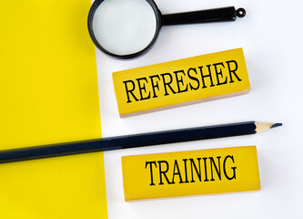 REFRESHER TRAINING - words on wooden yellow blocks with pencil and magnifying glass