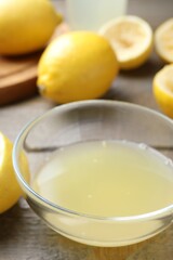 Bowl with fresh lemon juice and fruits on wooden table, closeup