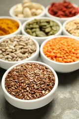 Different superfoods in bowls on grey table, closeup