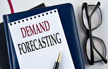 DEMAND FORECASTING - words on white sheet on light background with notebook and cactus