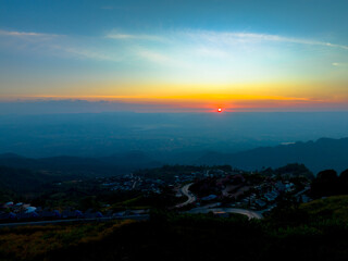 aerial view of a winding mountain road surrounded by lush greenery, scattered houses, and farmland. This scenic landscape captures the natural beauty and human settlement in a mountainous region.