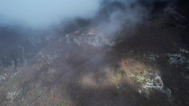 Flying Through Clouds Toward Mount Dajt, Bare Trees and Winter Forest on Rocky Slope Scene