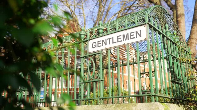 An old "gentlemen" sign on vintage public toilets under sunny skies, nostalgic design and outdated gendered restrooms