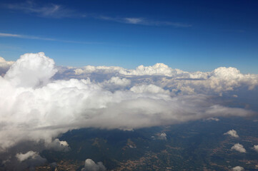 view from the window of an airplane with white clouds and mountains below