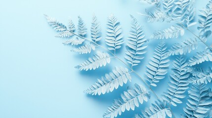 Pastel blue fern leaves on light blue background.
