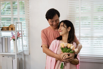 Elderly Couple Celebrating Valentine's Day with Flowers and Joyful Smiles in a Cozy Home Setting