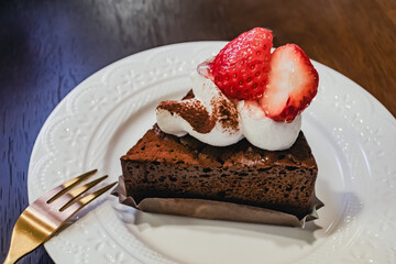 白皿に乗せた苺のケーキと金色のフォーク