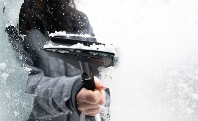 Driver is removing snow from car windshield with ice scraper and broom, clean car window from icy...