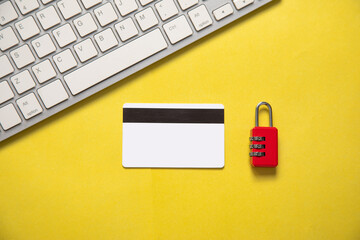 Padlock, credit card, computer keyboard on the yellow background.