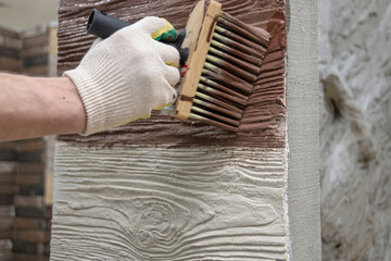Painting textured plaster with a brush, close up.