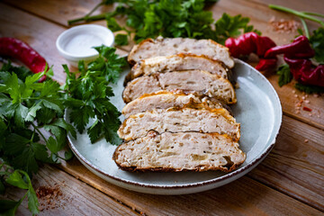 Pieces of stuffed fish on a light plate on a wooden table. Gefilte fish for dinner. Close-up.