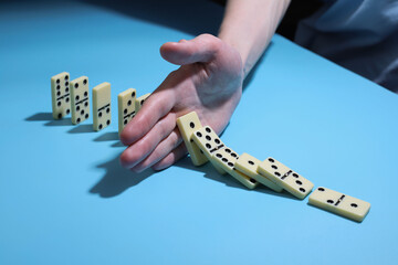 domino game. on a blue background there are light dominoes and a hand between them