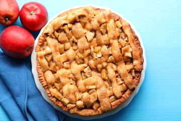 Homemade apple pie and apples on light blue wooden table, flat lay