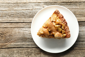 Slice of homemade apple pie on wooden table, top view. Space for text