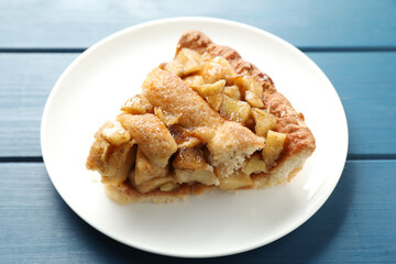 Slice of homemade apple pie on blue wooden table, closeup