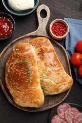 Delicious fresh calzone pizza served on wooden table, flat lay