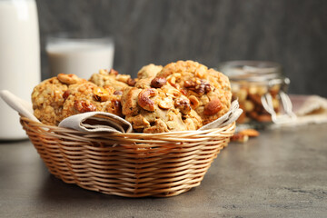 Tasty cookies with nuts in wicker basket on grey table, closeup. Space for text