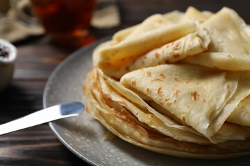 Tasty crepes on wooden table, closeup view